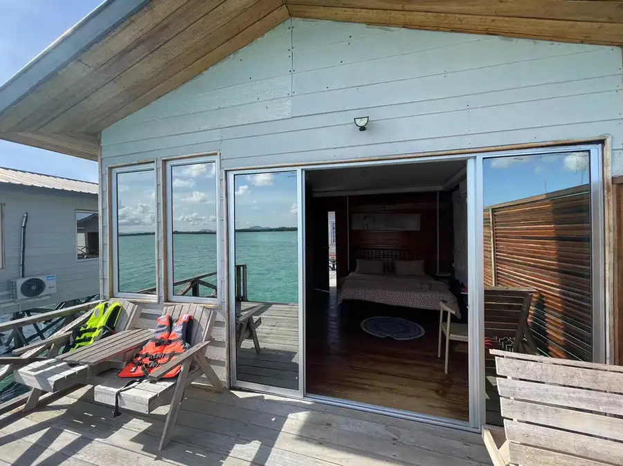 Private sunlit balcony with wooden loungers and life jackets at Fairyland Resort, a beautiful Semporna water resort set above crystal-clear waters offering a cool tropical breeze.