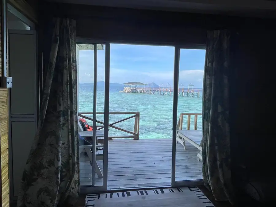 View through sliding glass doors to a private oceanview balcony at Fairyland Resort, a floating paradise near Semporna featuring breathtaking views of the Celebes Sea.