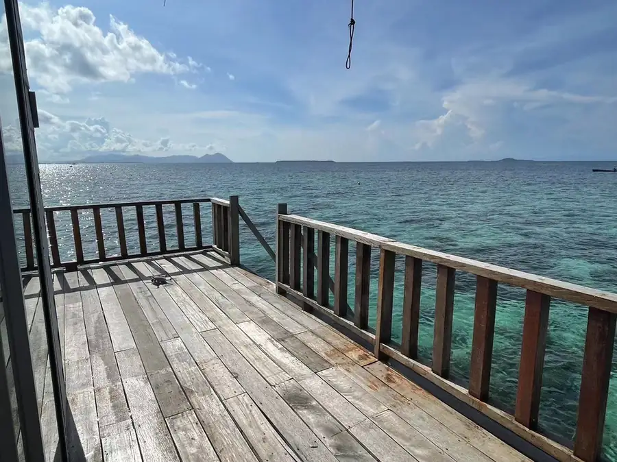 Private oceanview balcony with wooden loungers and direct stair access to the sea at Fairyland Resort. Set above crystal-clear waters, perfect for jumping into Tun Sakaran Marine Park.